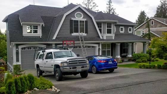 Gray home with gambrel roof and fresh white trim, work truck in the driveway
