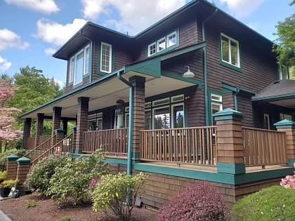 Brown home with green trim and refinished wooden deck railings